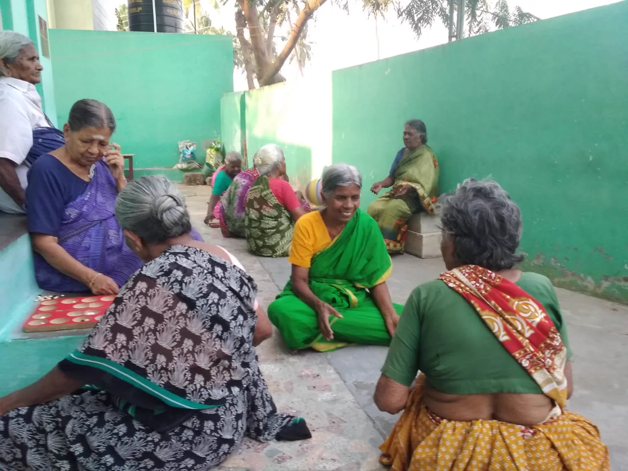 Residents sitting together along the wall of the courtyard